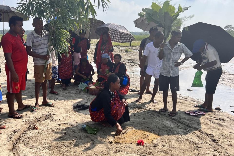 Men and women standing along the shores of a river