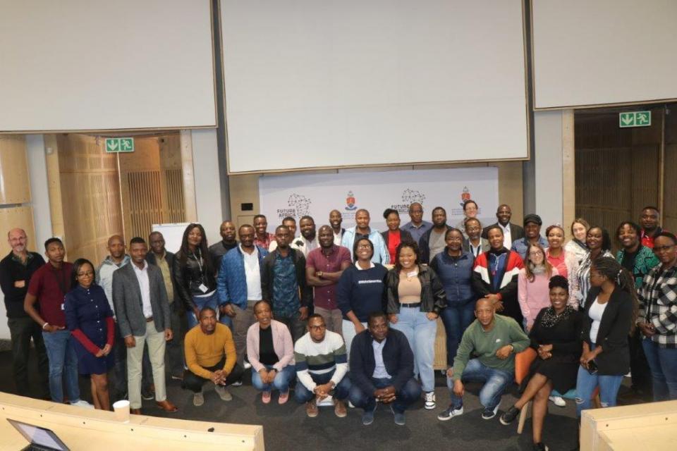 Group of people posing in front of whiteboards in class room